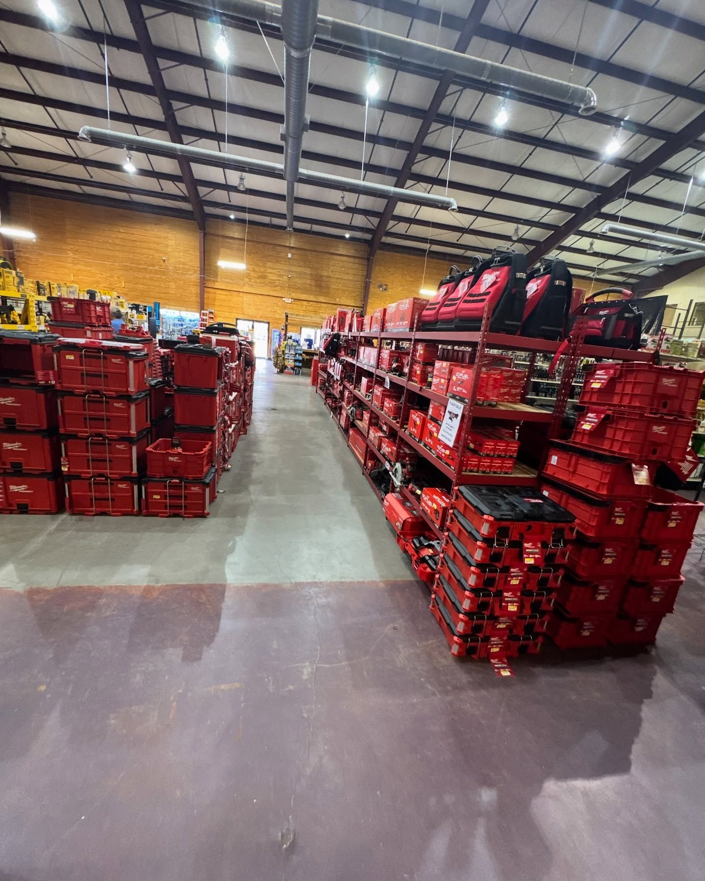 A long aisle in a warehouse store stocked with stacks and shelves of red Milwaukee tool storage cases and boxes.