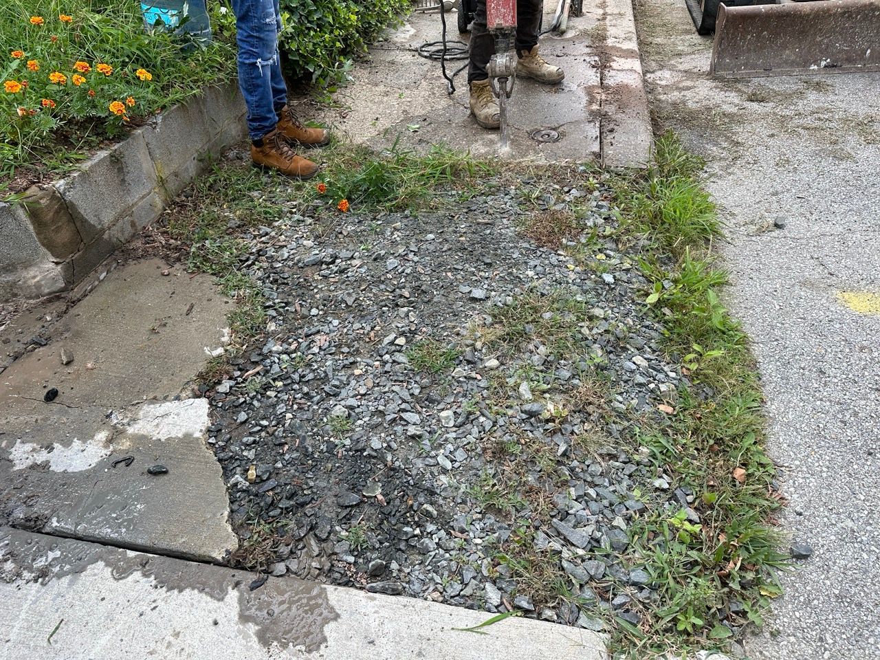 a man is standing next to a pile of gravel on the side of a road .