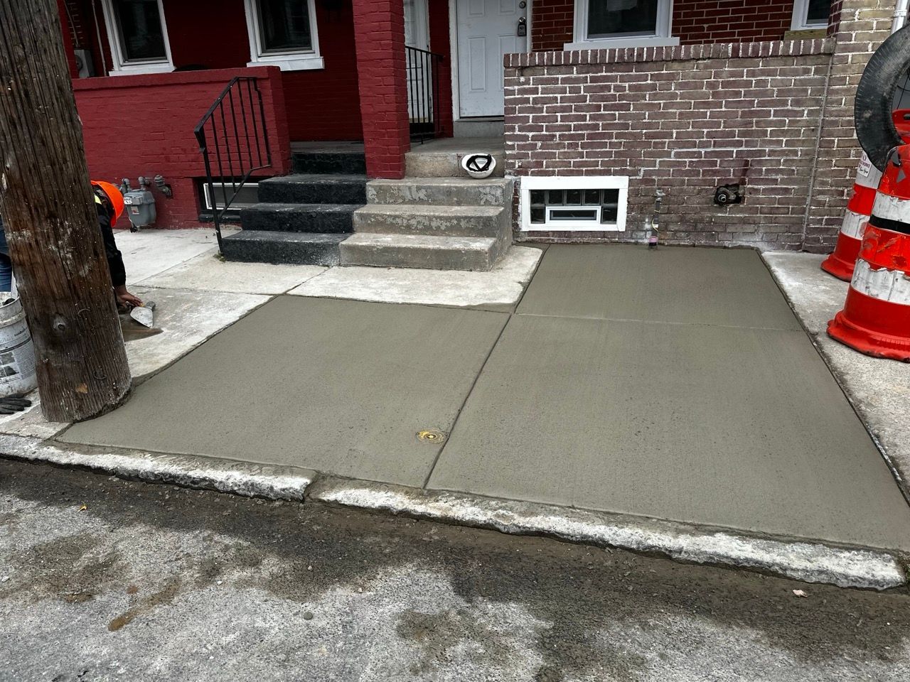 a concrete walkway is being built in front of a brick house .