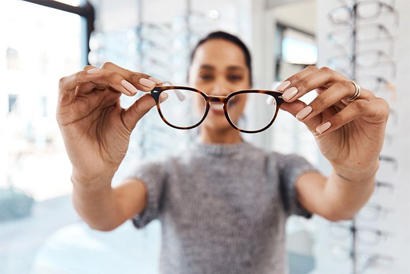 Person holding up round eyeglasses in a bright optical store