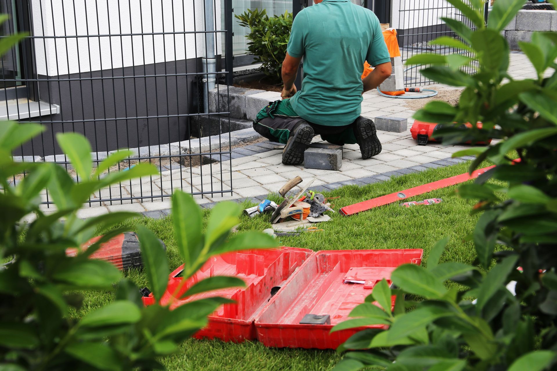Workers installing paving stones and landscaping materials in a newly constructed garden.