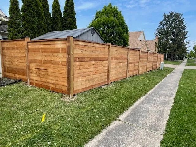 A wooden fence along a sidewalk next to a house.