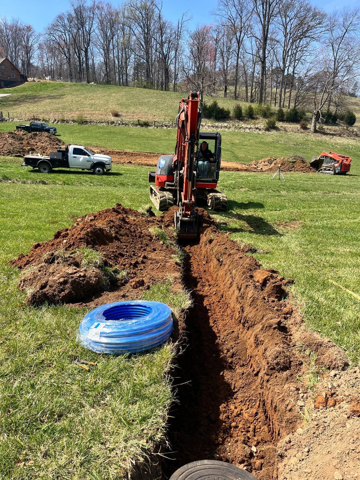 An excavator is digging a hole in the ground in a field.