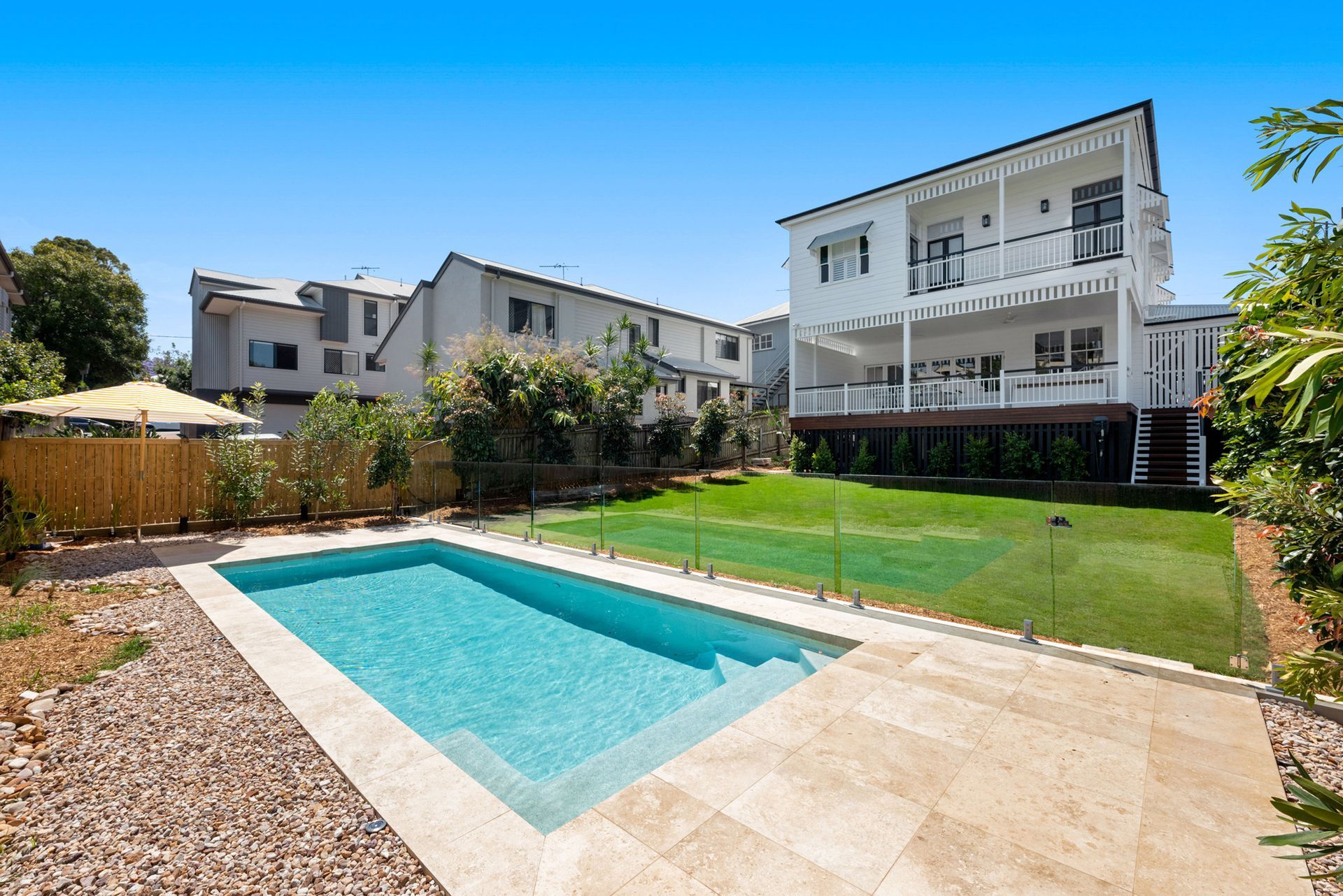 Backyard with a rectangular swimming pool beside a lawn and modern apartment buildings