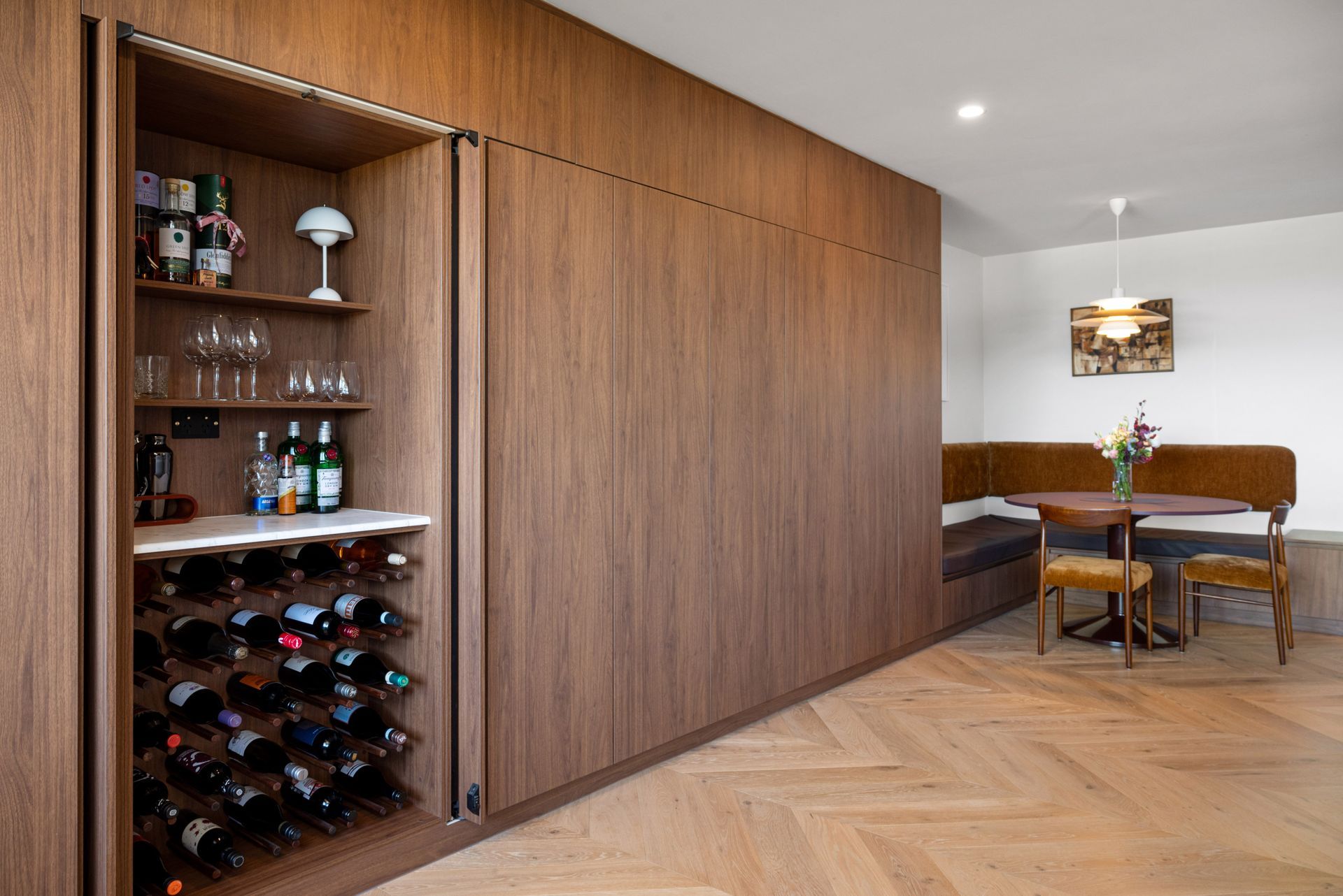 Modern wood-paneled dining room with built-in wine storage, table, chairs, and pendant light