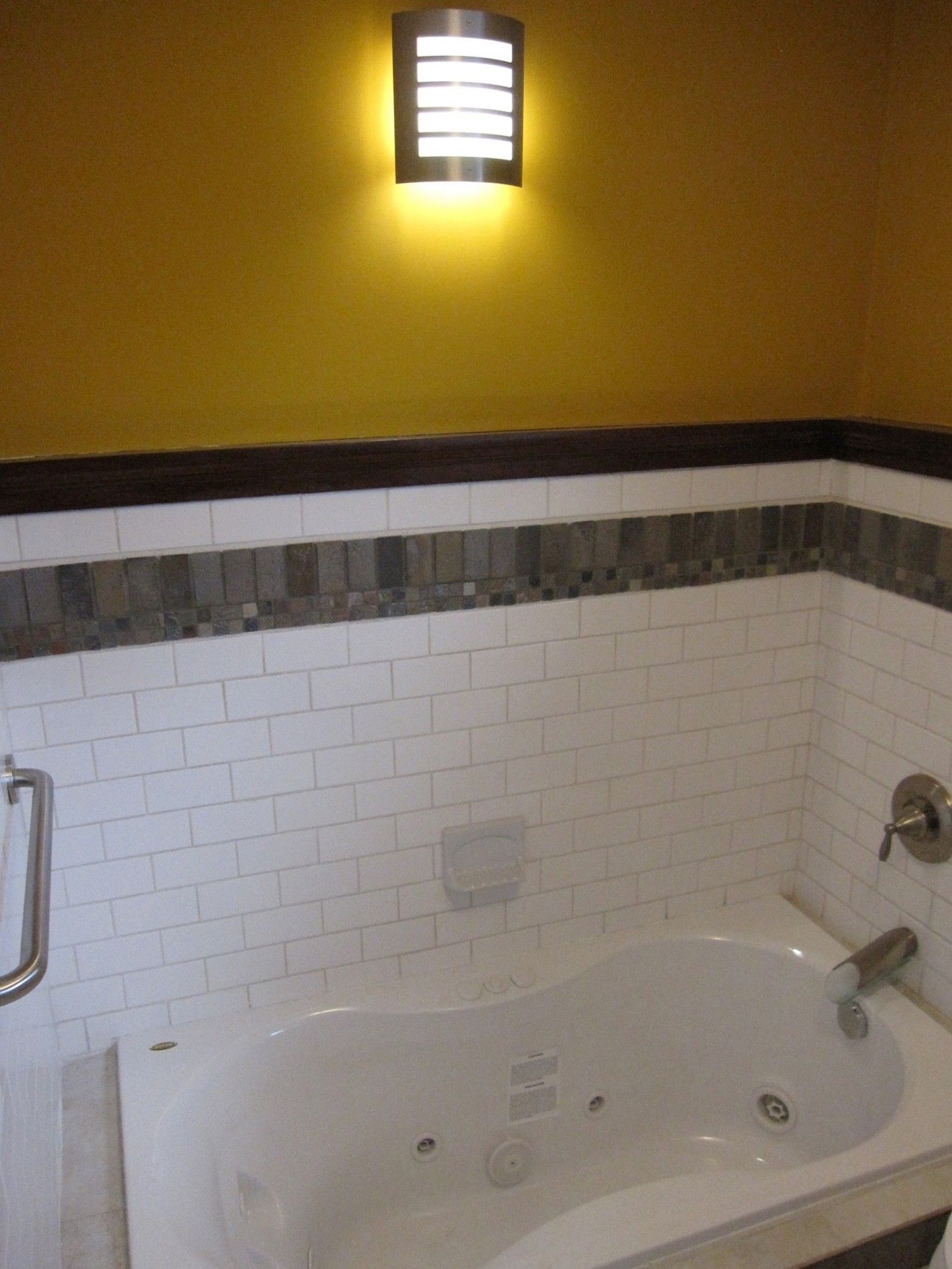 Bathroom with white subway tile, a jacuzzi tub, and yellow walls.