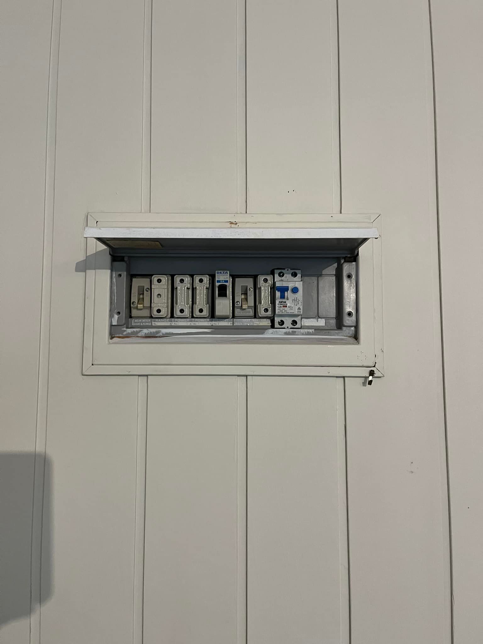 A White Electrical Panel With Breakers and Fuses Mounted — Neave Electrical in Forster, NSW