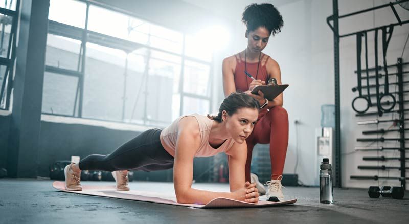 Woman in plank pose at gym  representing Why Clients Trust Their Trainer More Than Their Advisor 