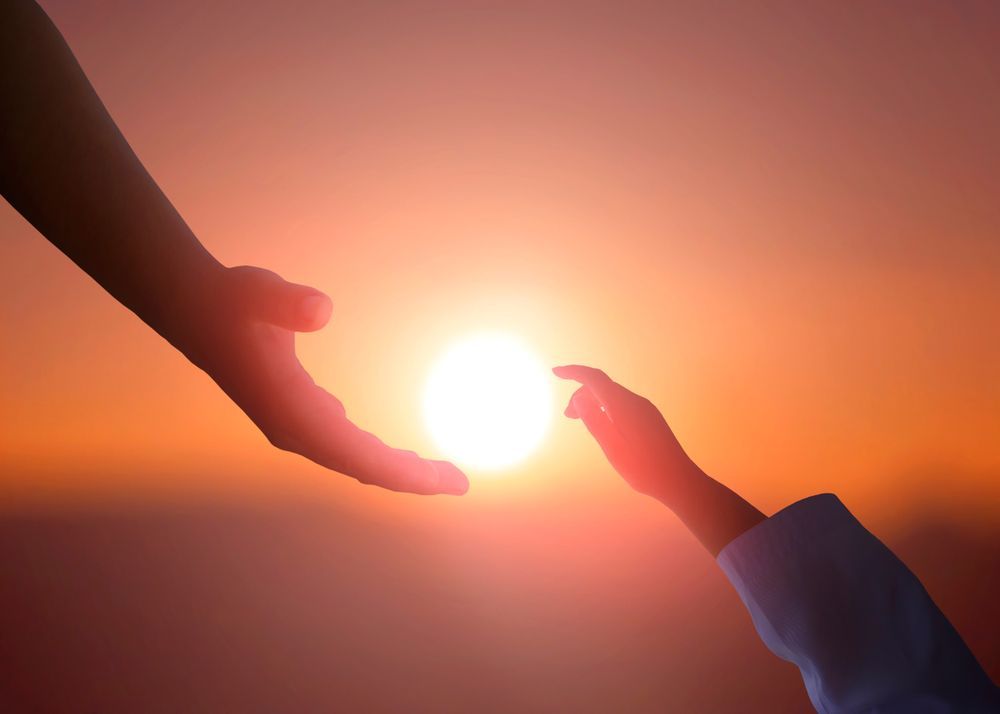 Two hands reaching toward a bright sun at sunset, silhouetted against an orange sky — Ashes to Ashes Cremations In Mooroobool, QLD