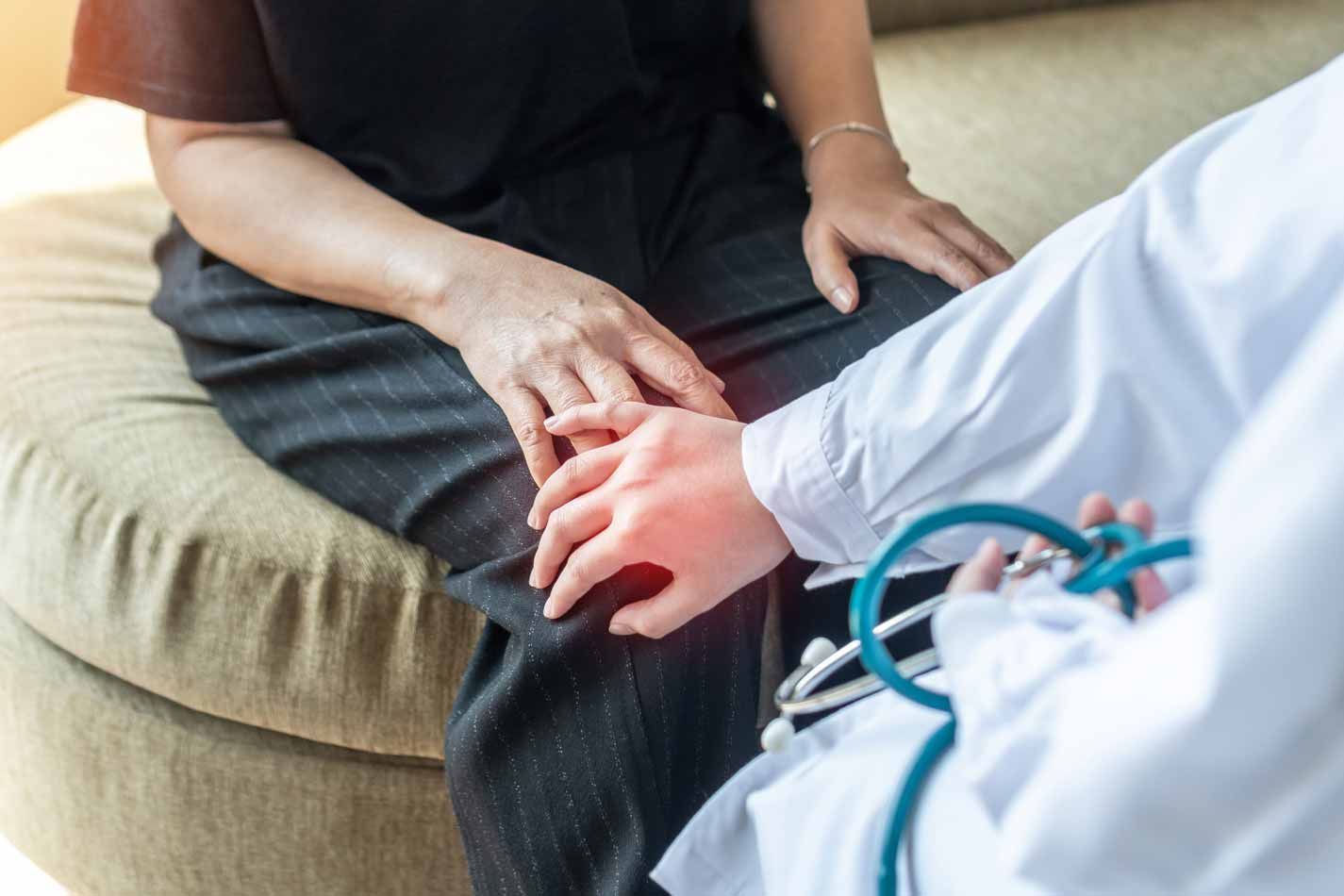 Therapist holding a client’s hand during a counseling session on a couch