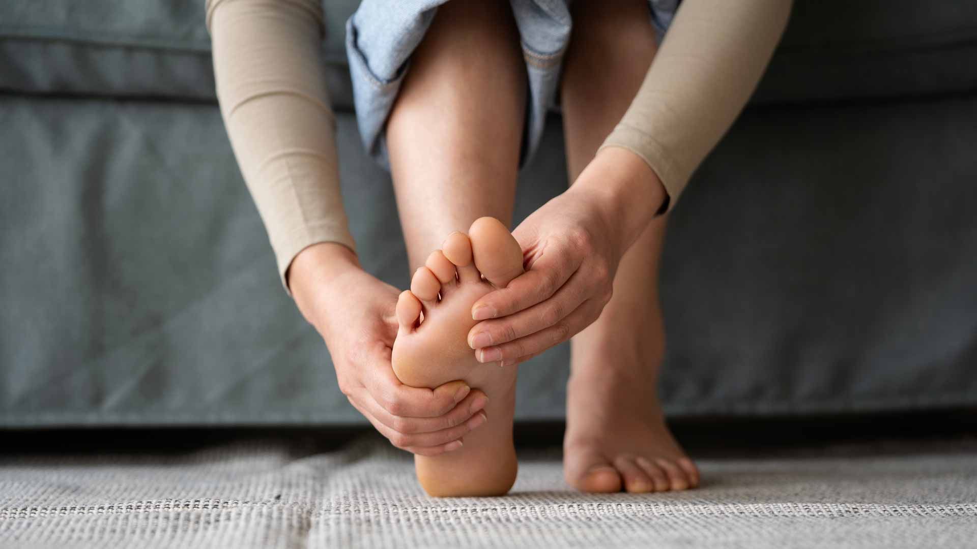 Person holding the sole of another person's foot while sitting on a rug indoors
