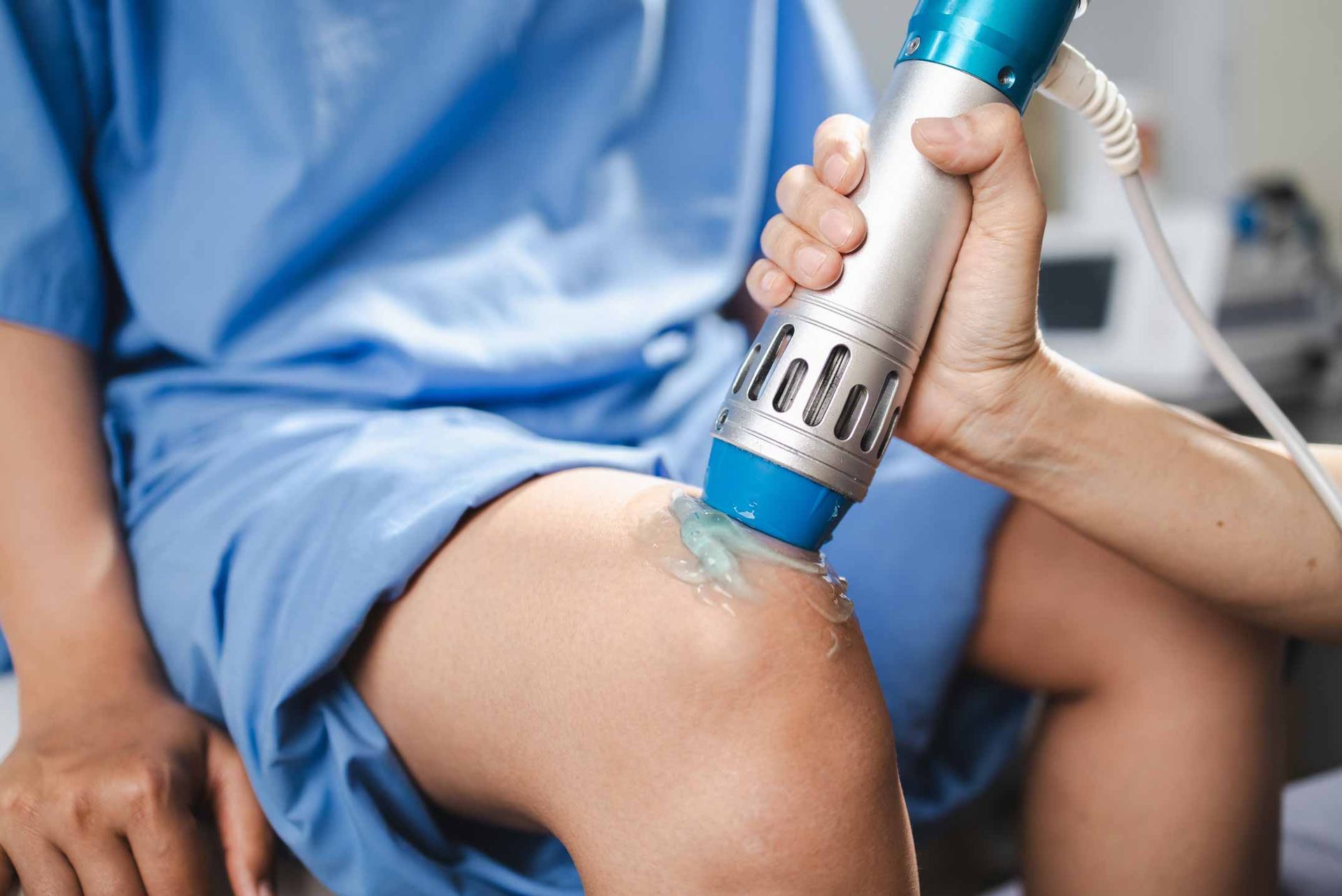 Physical therapist using a handheld ultrasound device on a patient’s knee in a clinical setting