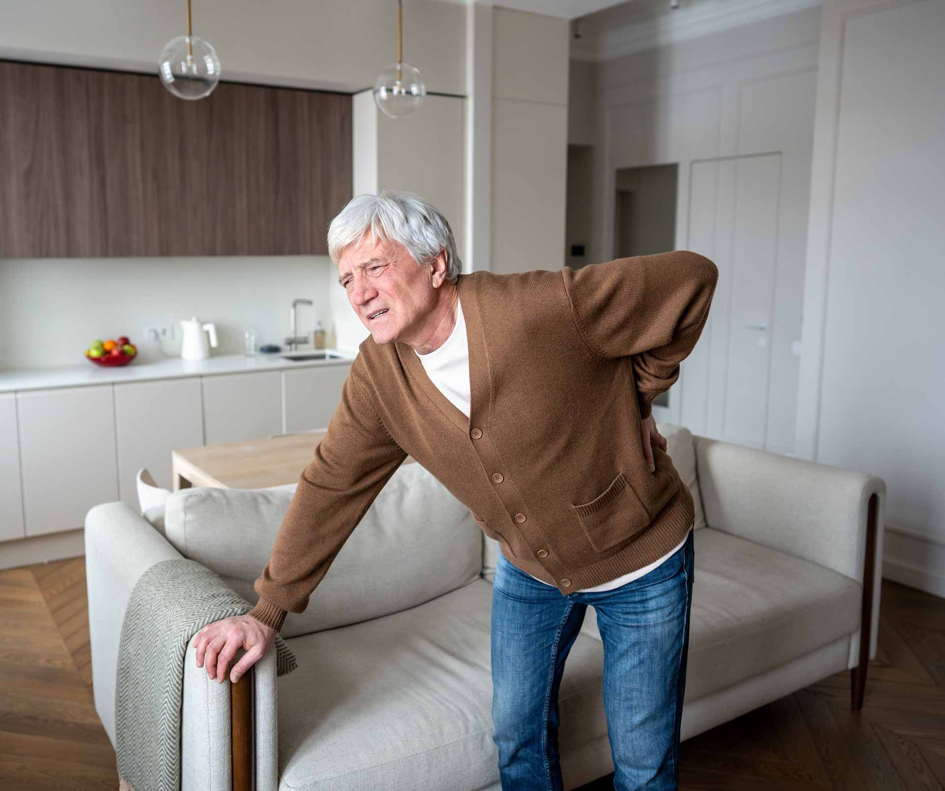 Smiling man leaning on a sofa arm in a bright modern living room