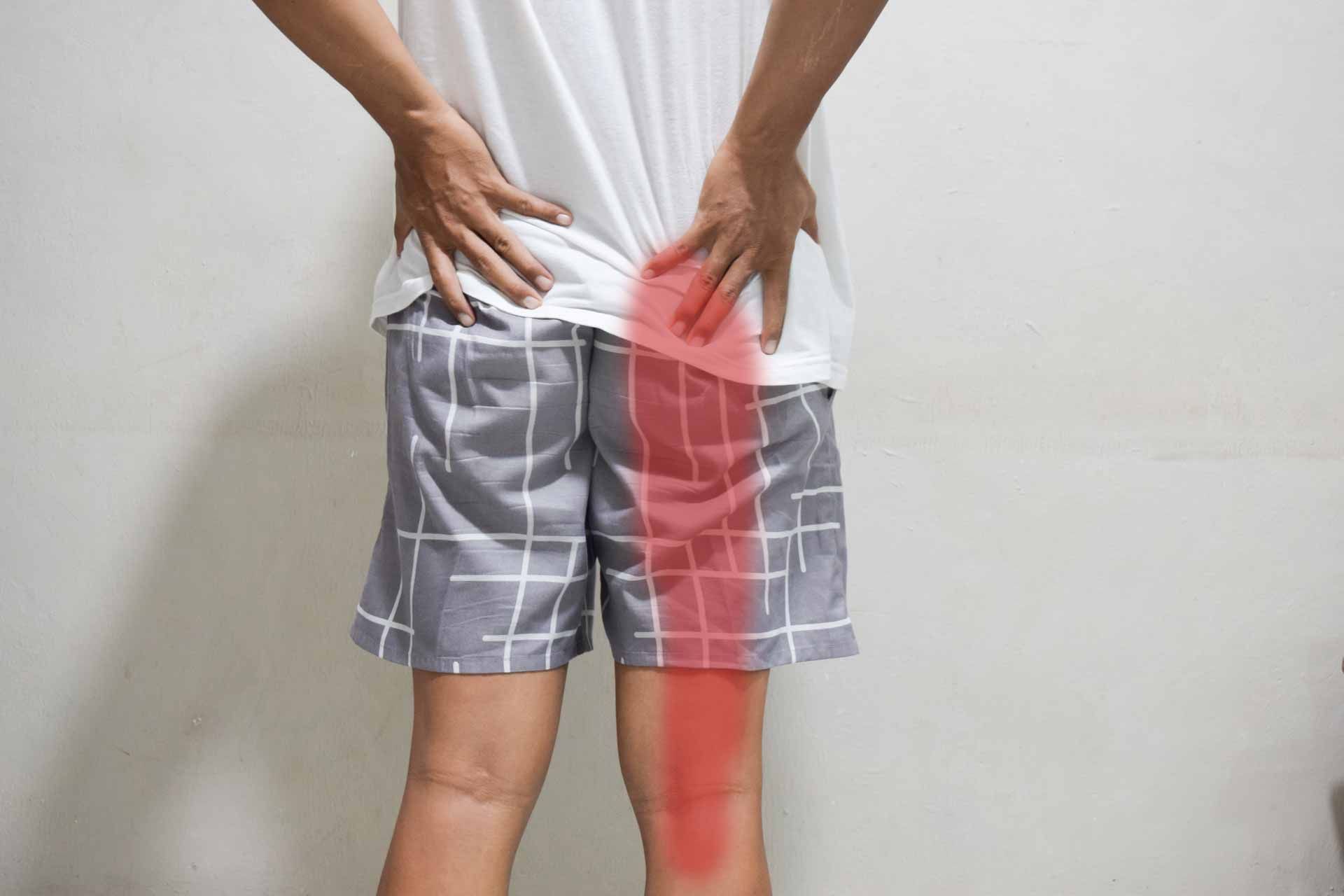 Person holding lower back, with red highlight over the right hip and thigh to show pain area.