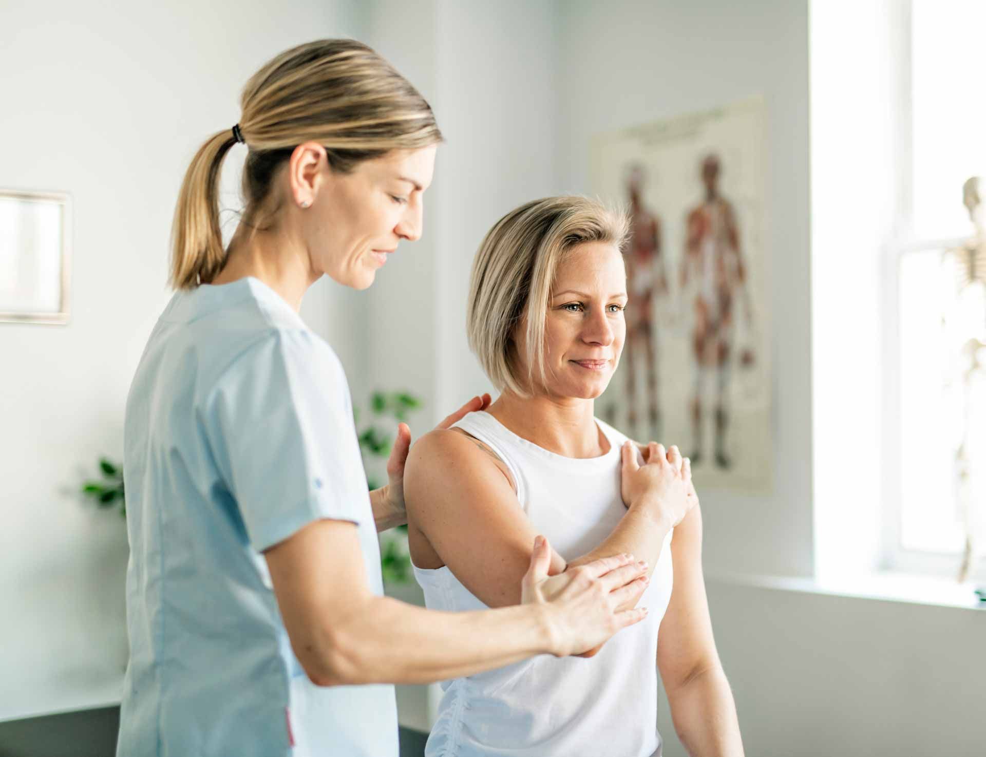 Physical therapist guiding a patient through arm exercise in a bright clinic room