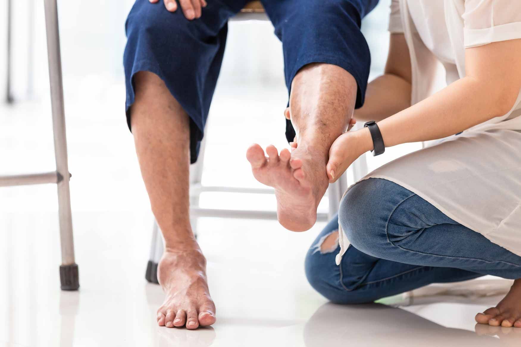 Therapist examining a patient’s injured ankle during a home visit
