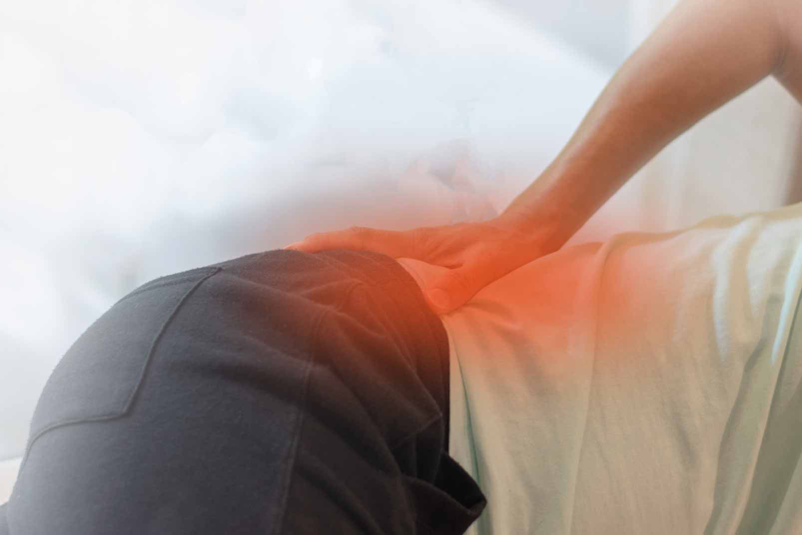 Hand holding lower back with red glow, suggesting pain or injury