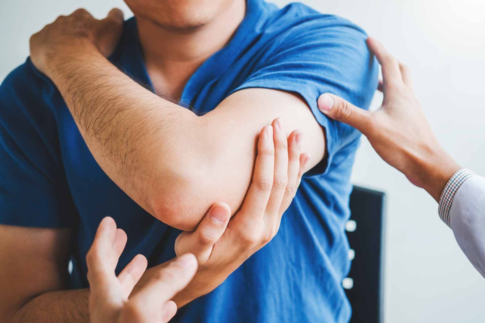 Two hands examining a person’s bent elbow and forearm in a clinical setting