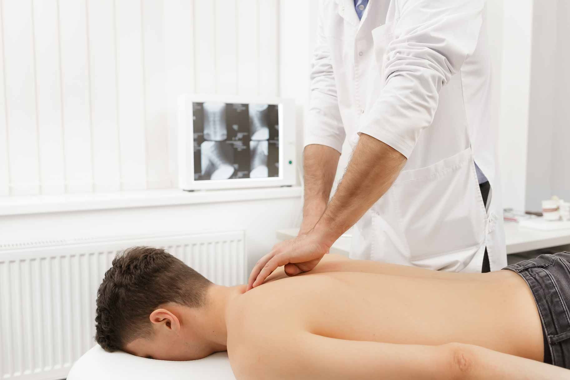 Massage therapist working on a client’s back in a bright clinic room