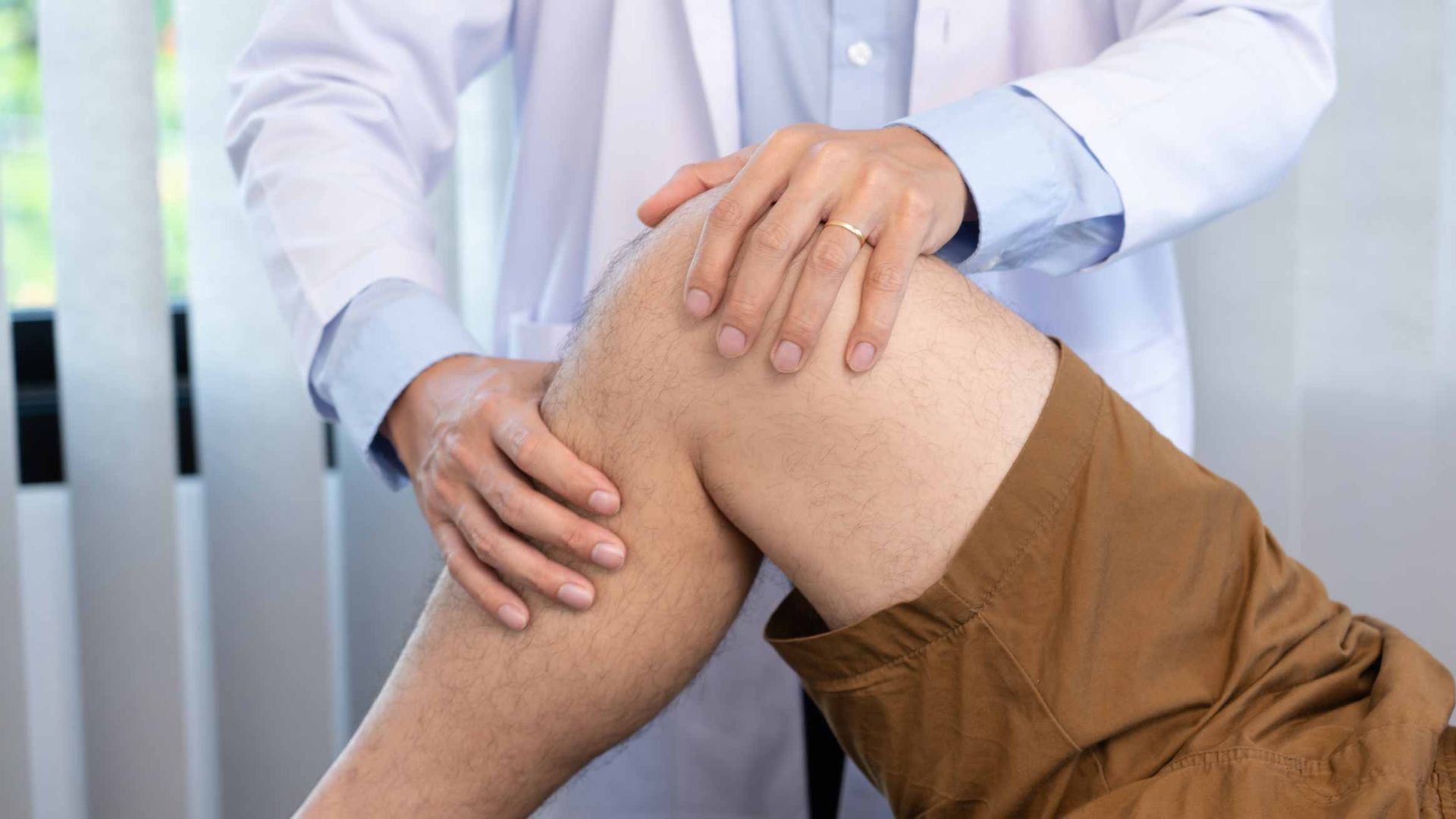 Doctor examining a patient's bent knee in a clinic setting