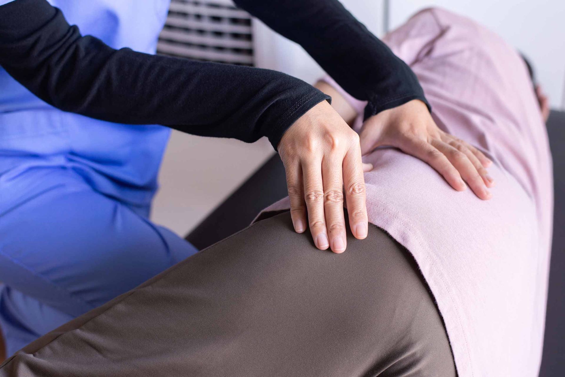 Physical therapist examining a patient’s lower back during treatment