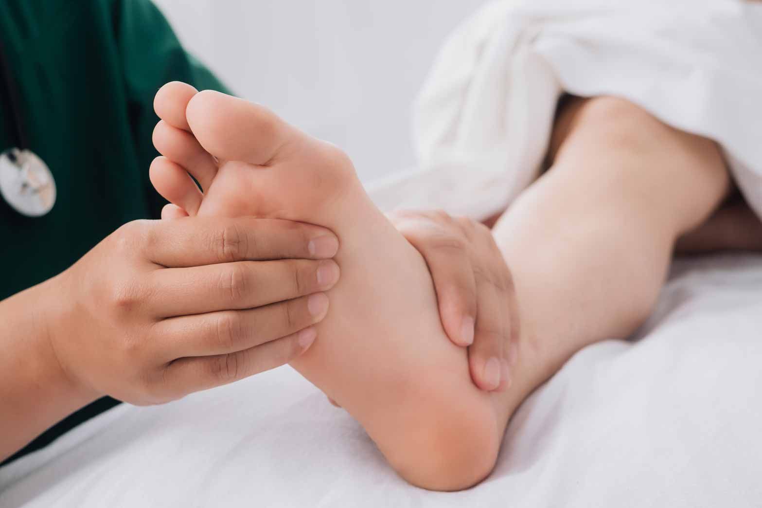 Hands massaging a person's foot on a massage table