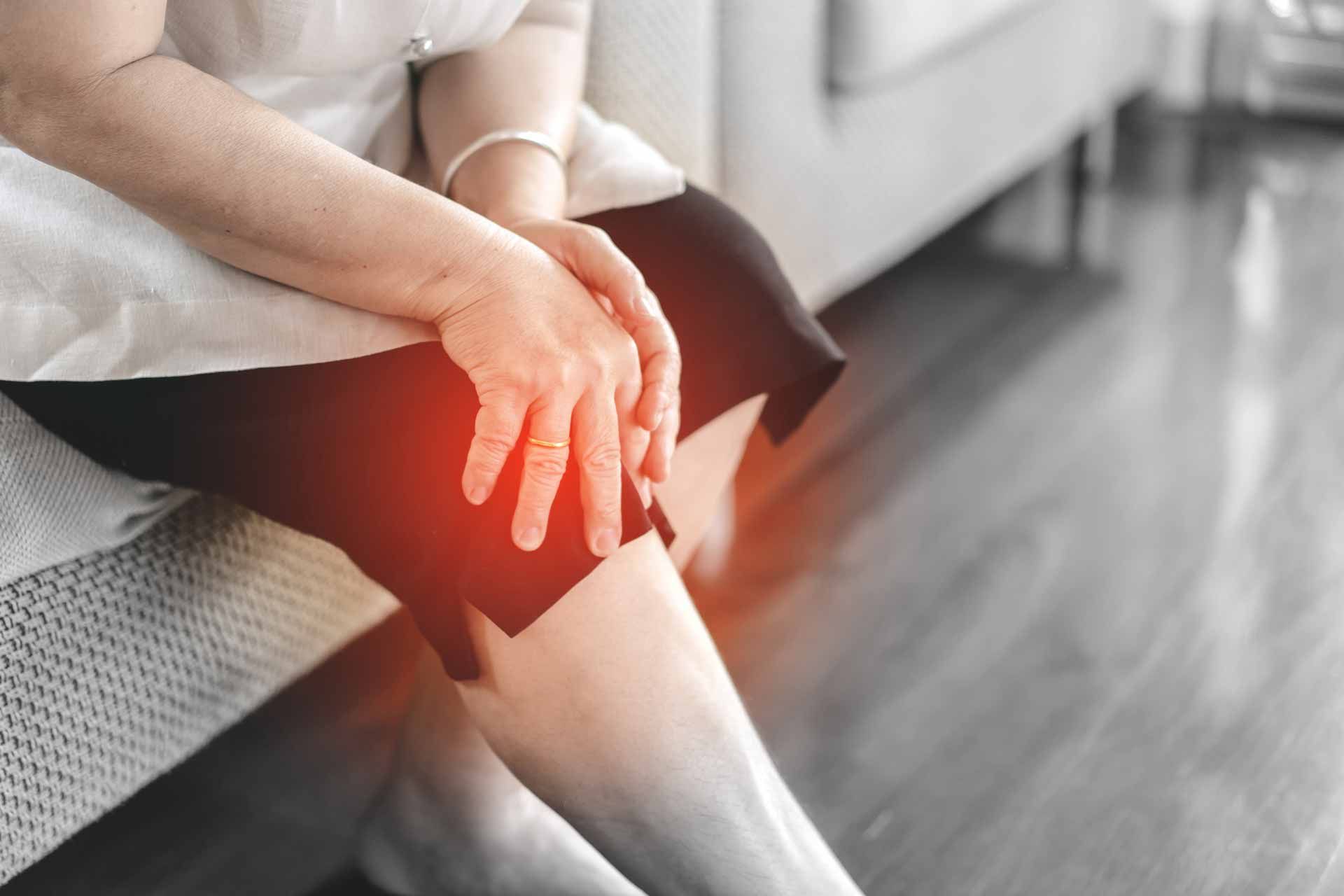Person holding a painful knee with red glow highlighting the injury