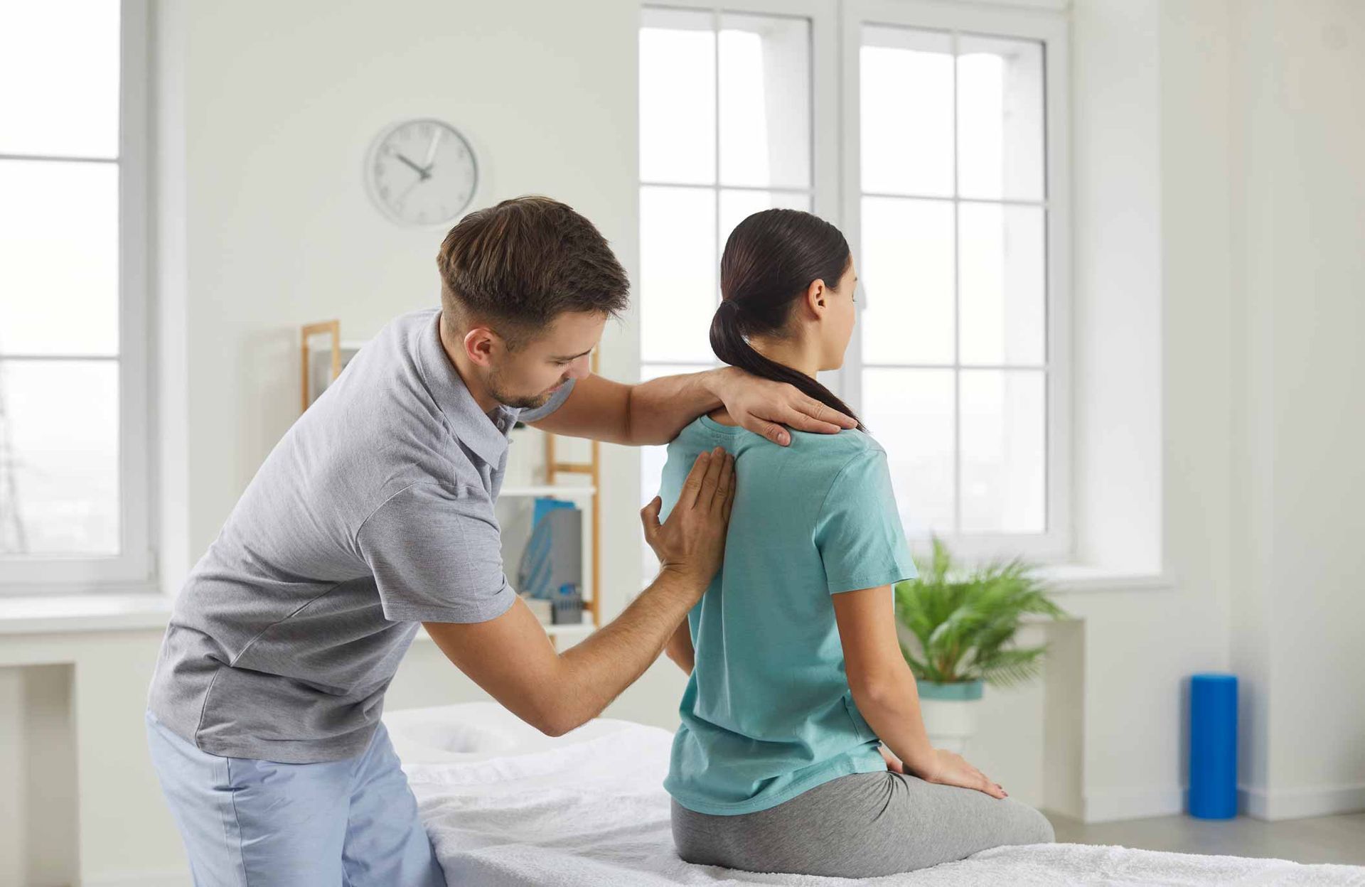 Physical therapist guiding a patient’s shoulder stretch in a bright clinic room