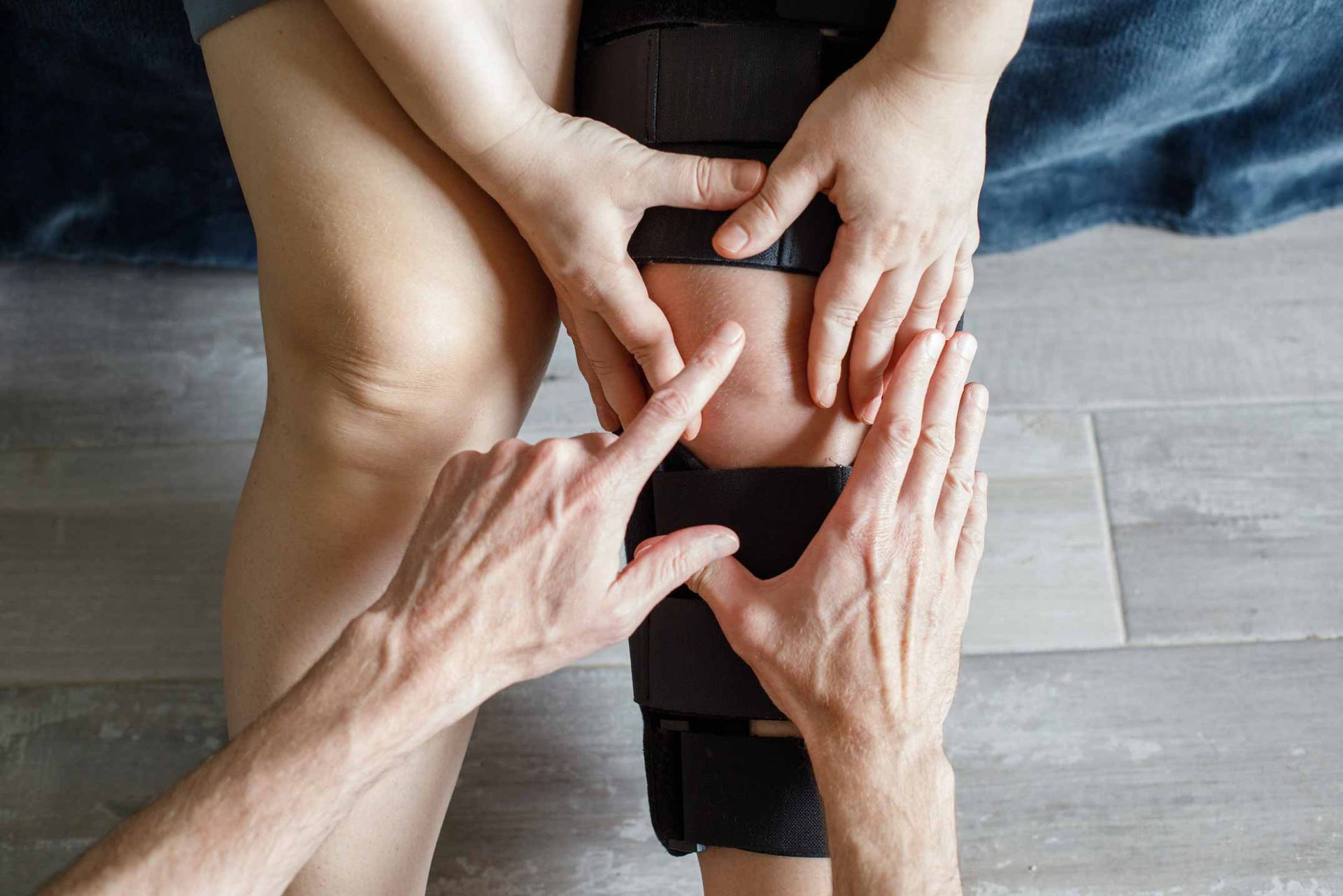 Hands pressing and stretching a person’s bent knee during a floor exercise or physical therapy session