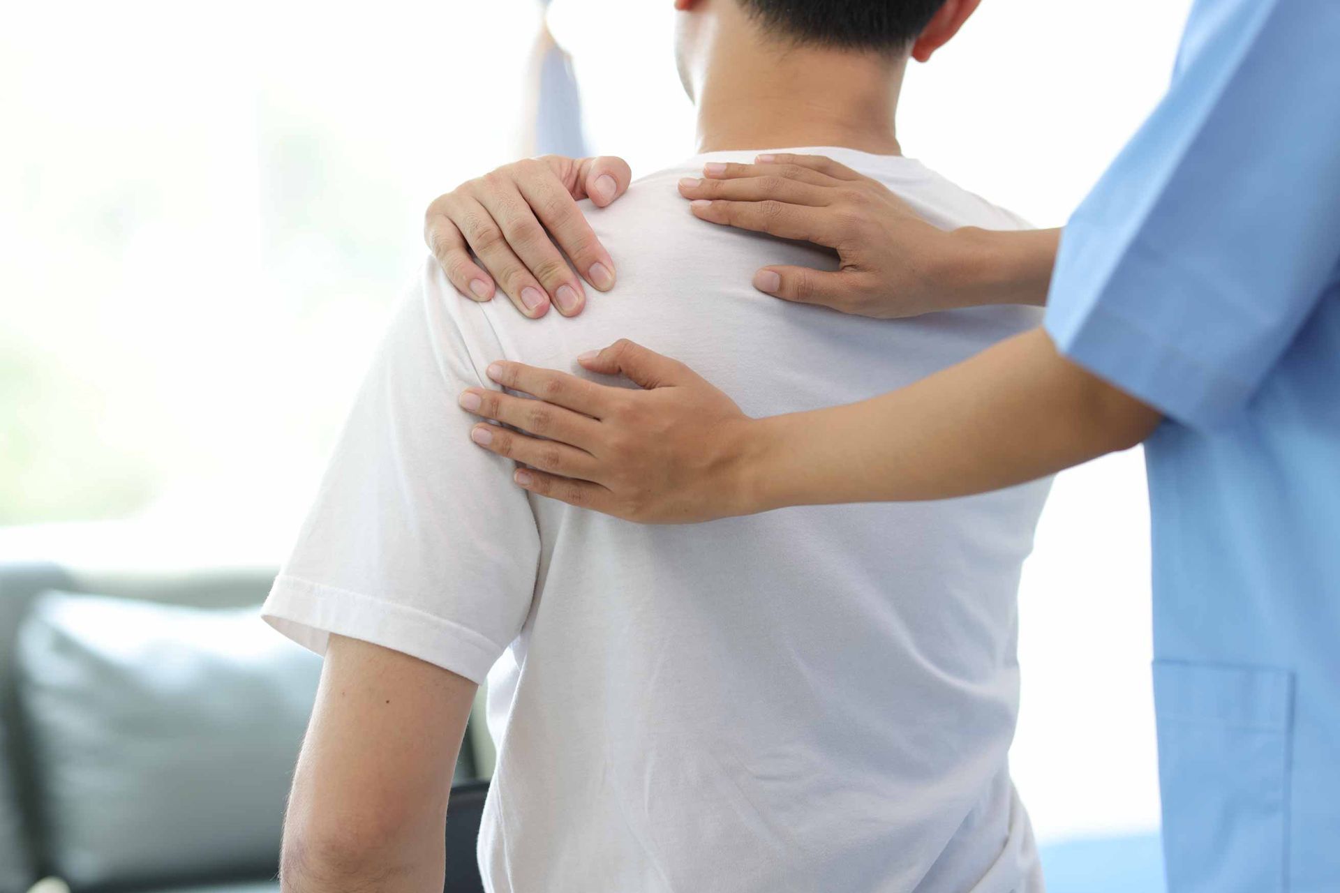 Medical professional supporting a seated patient from behind with hands on shoulders