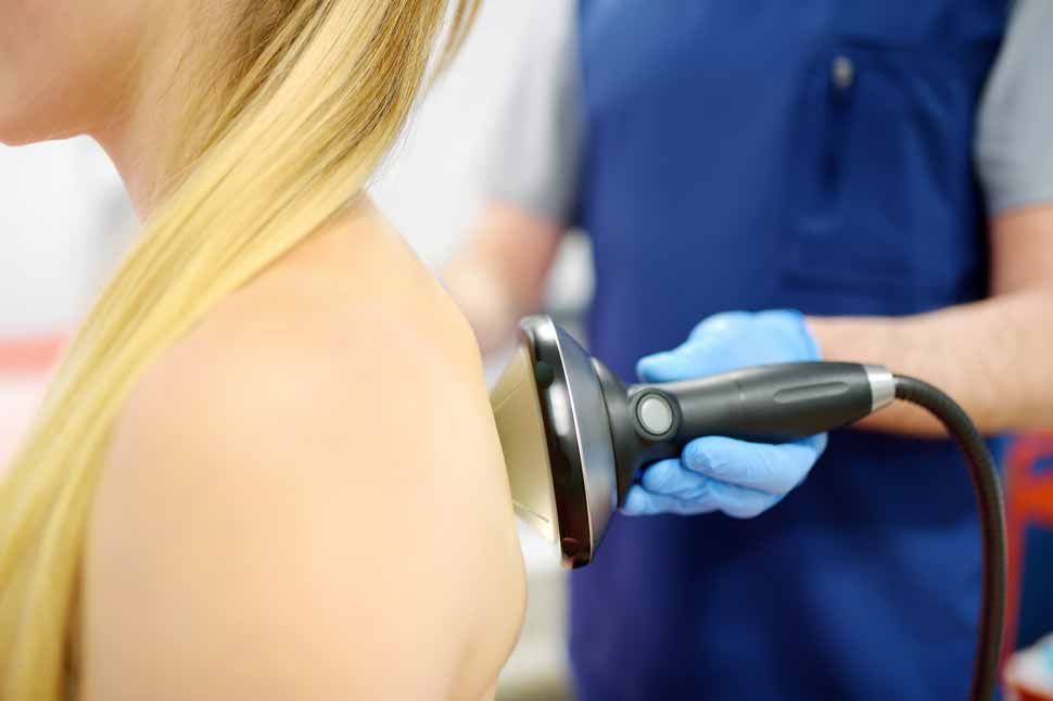 Physical therapist applying ultrasound therapy to a patient’s shoulder