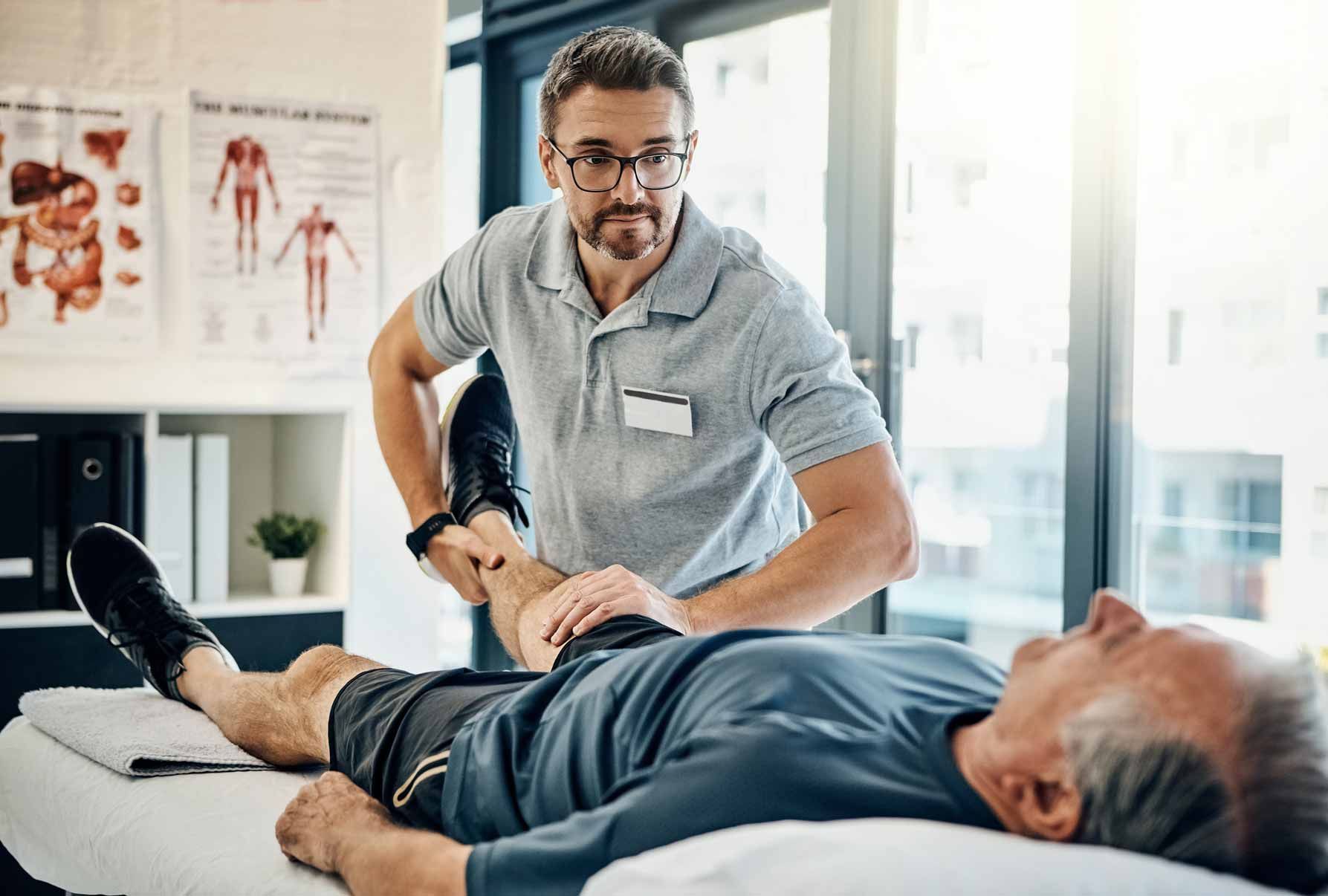 Physical therapist treating a patient on a clinic table during a leg exam