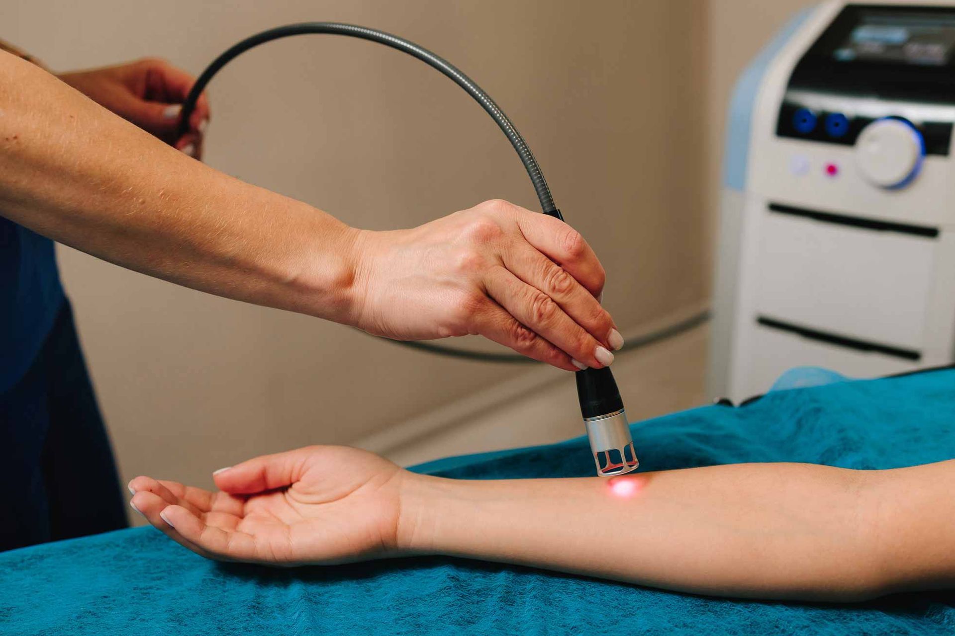 Handheld laser therapy applied to a person’s forearm in a clinical setting