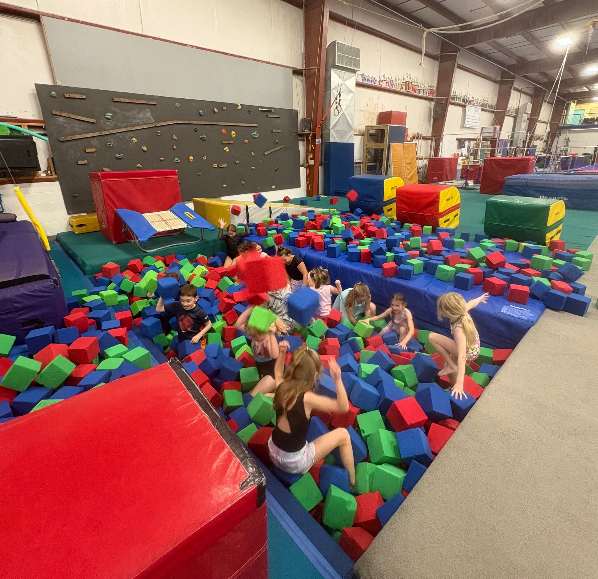 Children playing in a colorful foam pit at an indoor gymnastics gym
