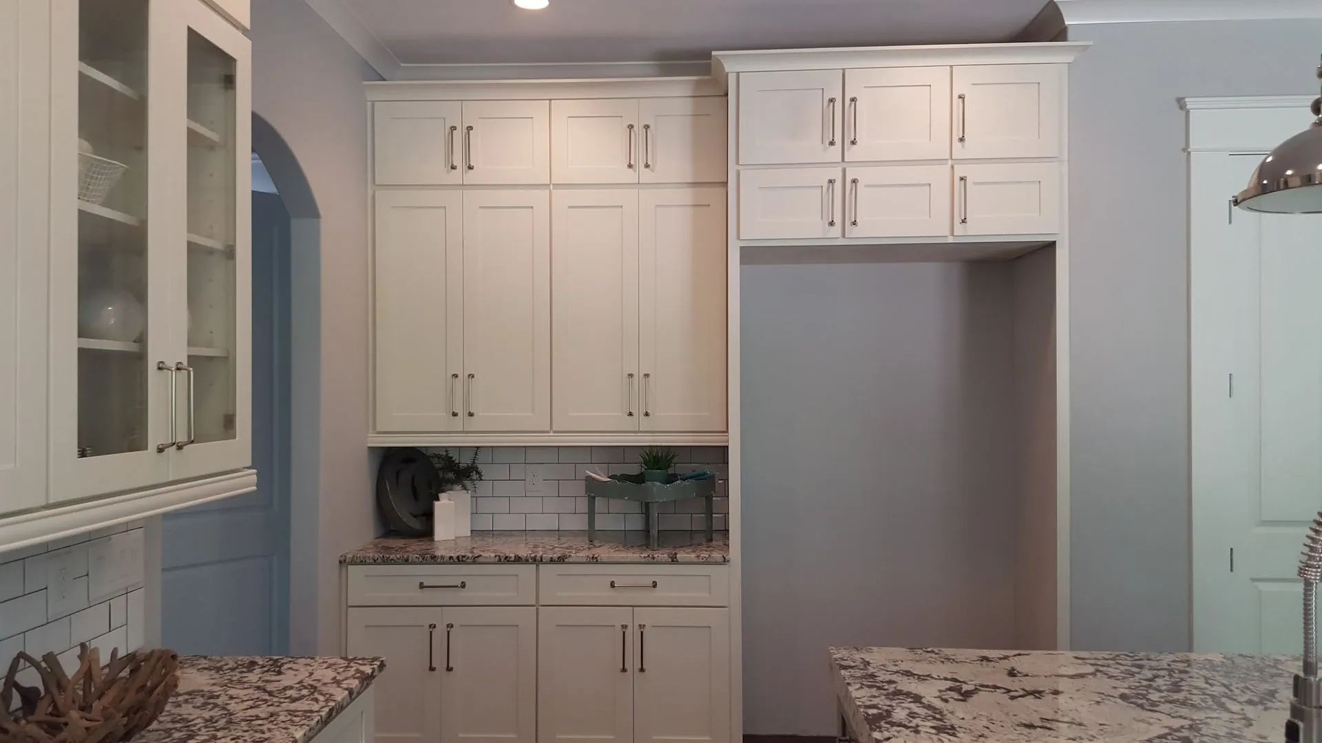 Bright white kitchen with cabinets, countertops, and a built-in refrigerator niche.