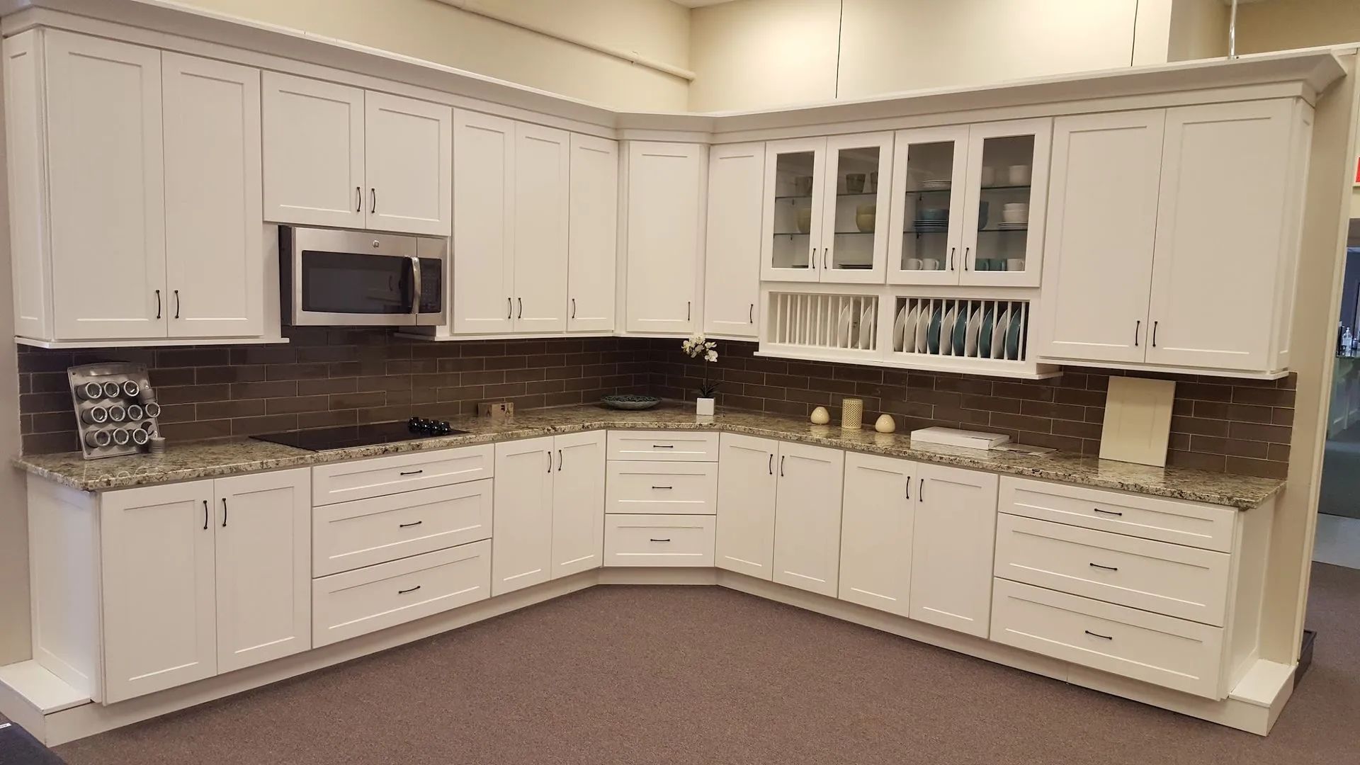 White kitchen cabinets with granite countertops and a tiled backsplash.