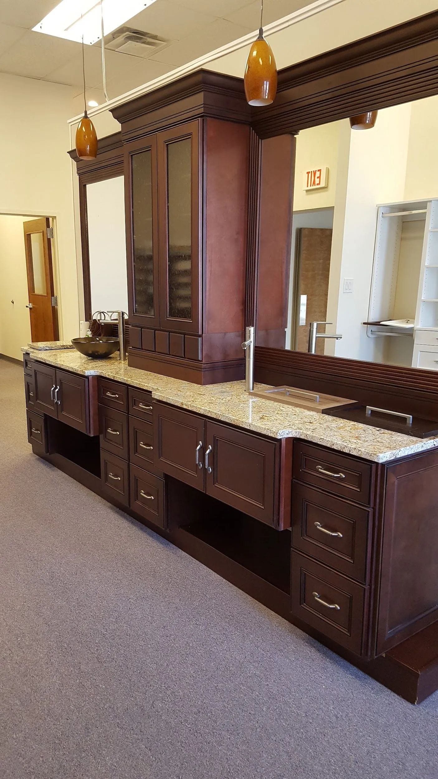 Dark wooden antique vanity with mirrors and drawers in a carpeted hallway, lit by hanging lamps