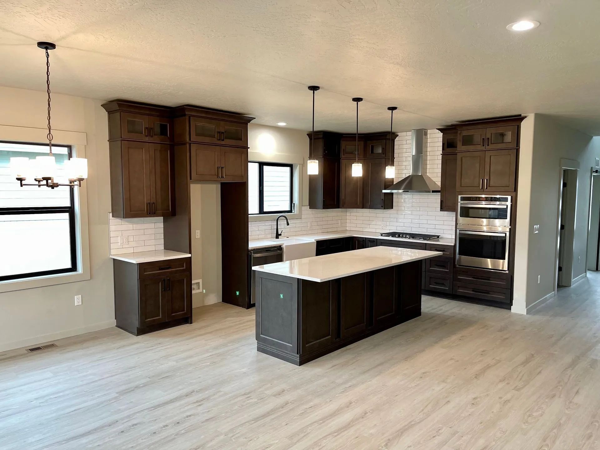 Modern kitchen with dark wood cabinets, white countertops, and island.