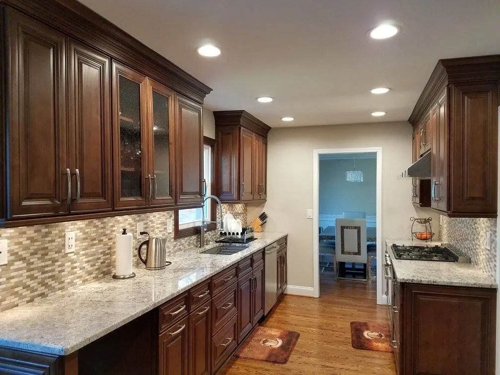 Modern kitchen with dark wood cabinets, granite counters, mosaic backsplash, and recessed lighting