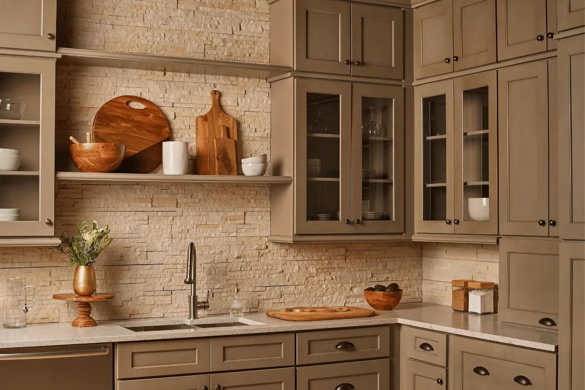 Kitchen with stone backsplash, gray cabinets, open shelving, and stainless steel sink.