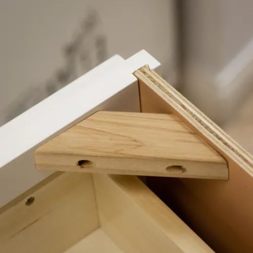 Wooden corner bracket reinforcing furniture joinery.