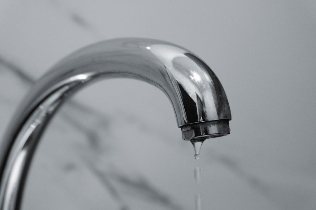 Dripping chrome faucet against a gray marble background