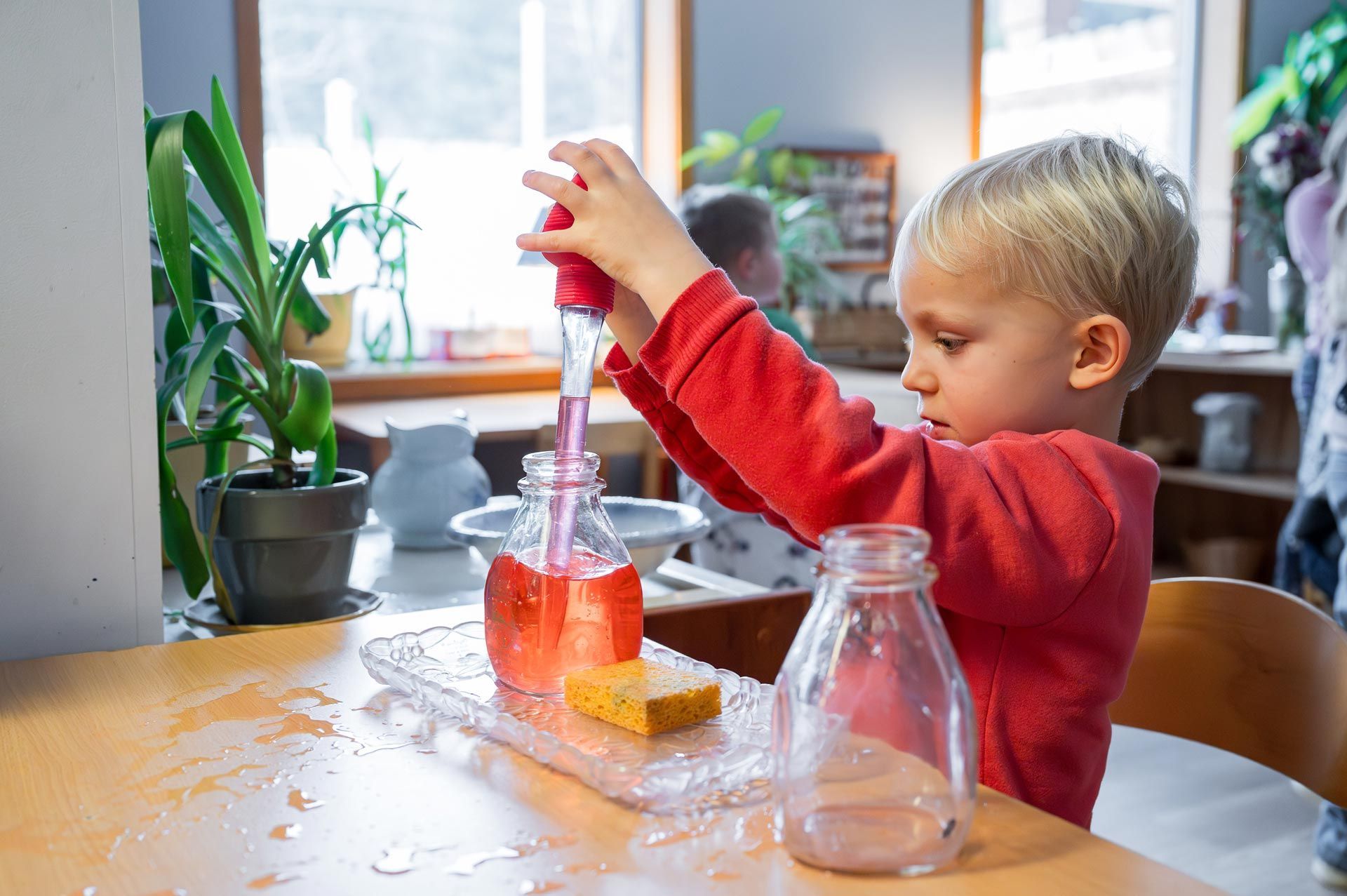 Montessori child transferring liquid with a dropper in a classroom setting