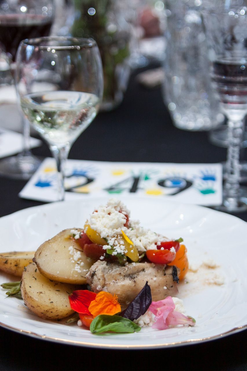 Gourmet plated dish with garnishes on a white plate at a restaurant table with wine glasses