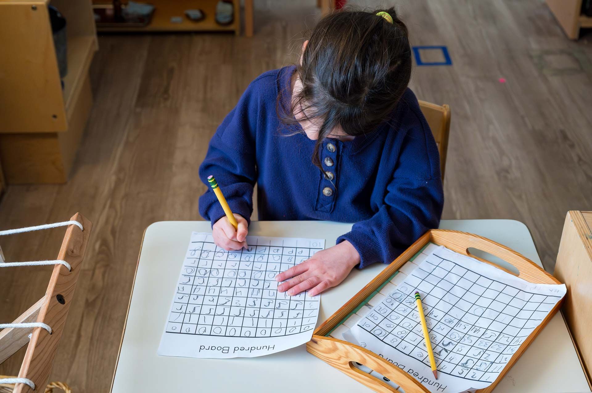 montessori child working on a hundred board activity at a classroom table