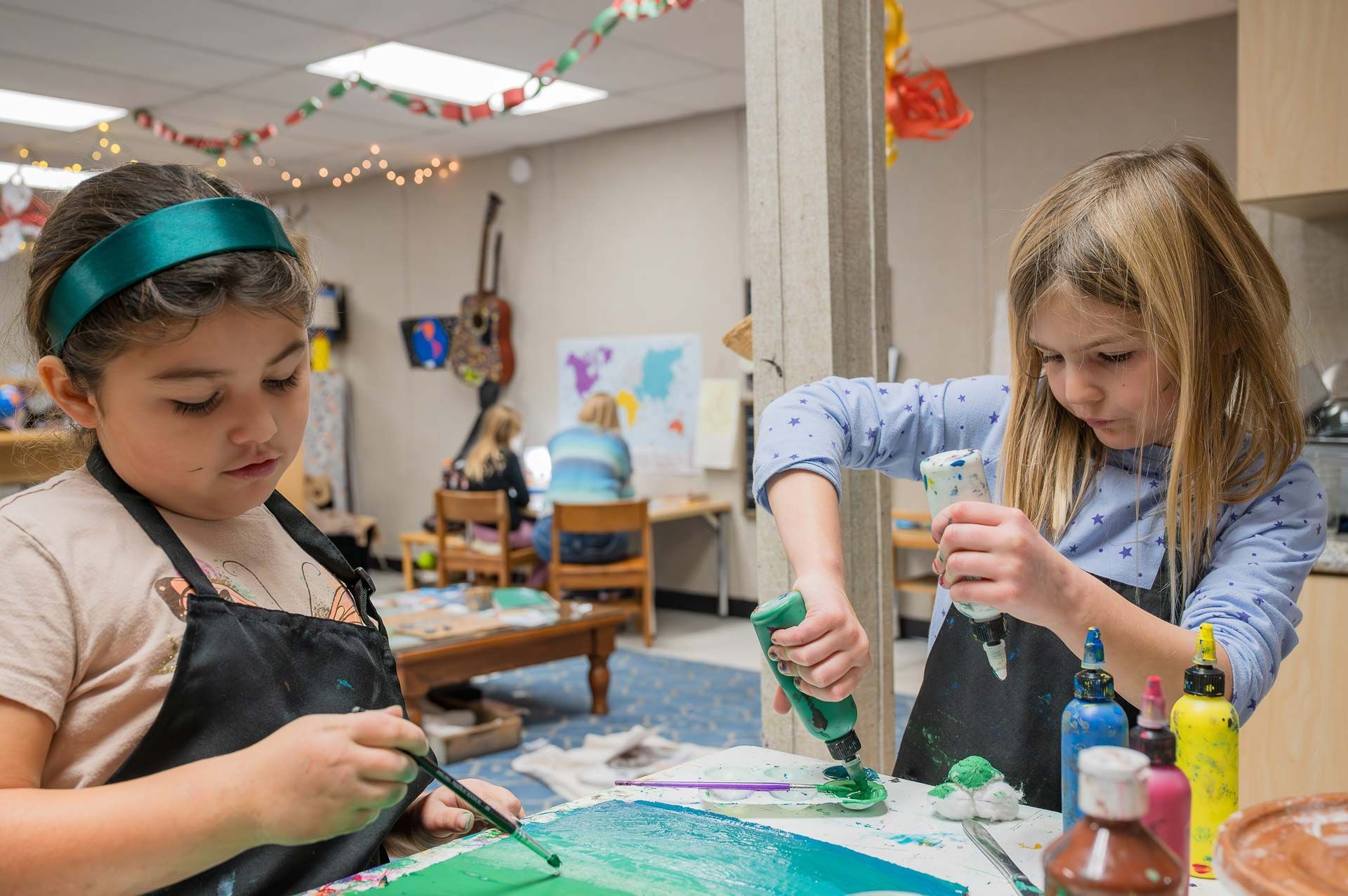 montessori children painting at a table with colorful supplies in a creative classroom setting