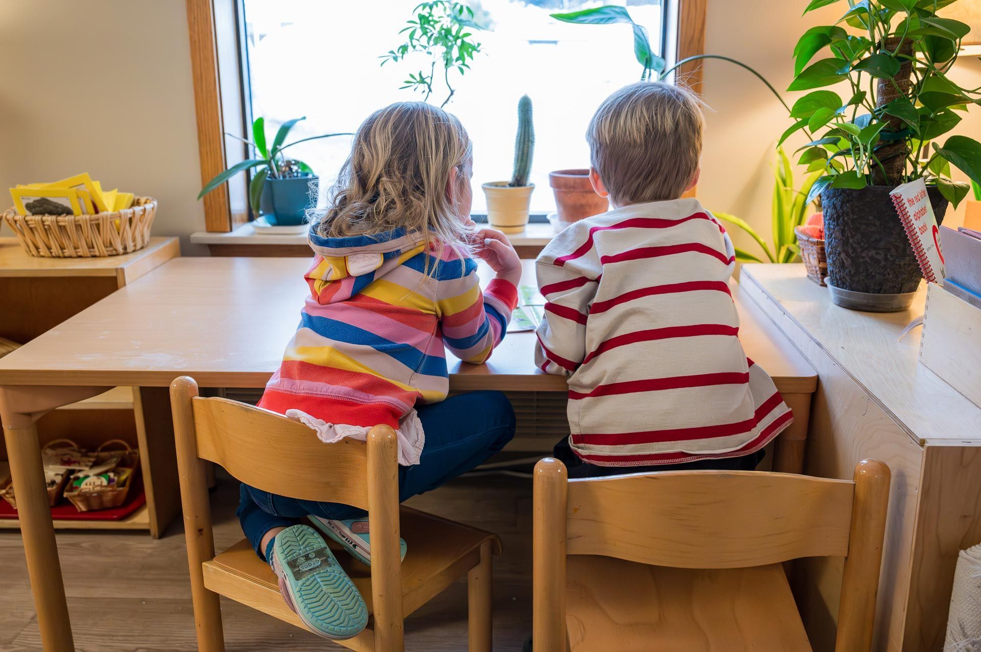 two montessori children sitting at a table in a classroom setting