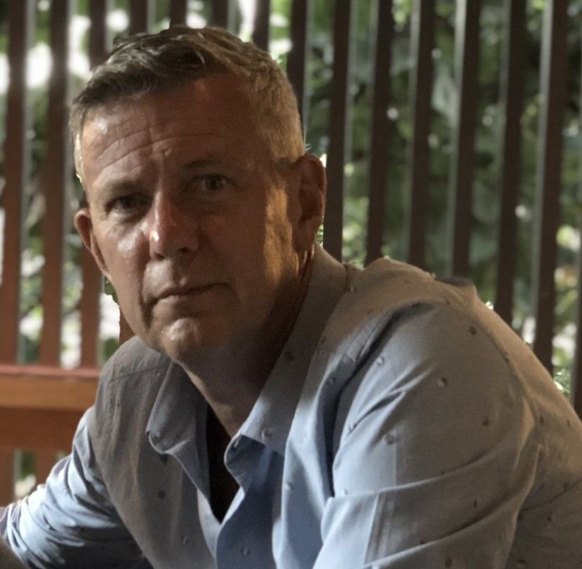 A man in a blue shirt is looking at the camera
