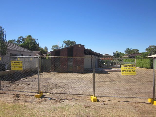 A fenced in area with a house in the background