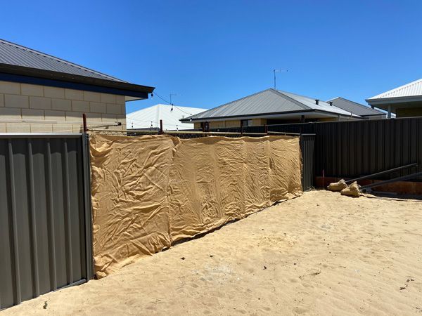 A fence is being built in the backyard of a house.
